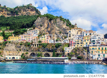 Panoramic view, aerial skyline of small haven of Amalfi village with tiny beach and colorful houses located on rock. Tops of mountains on Amalfi coast, Salerno, Campania, Italy. Panoramic view, aerial skyline of small haven of Amalfi village with tiny beach and colorful houses located on rock. Tops of mountains on Amalfi coast, Salerno, Campania, Italy. 131477736
