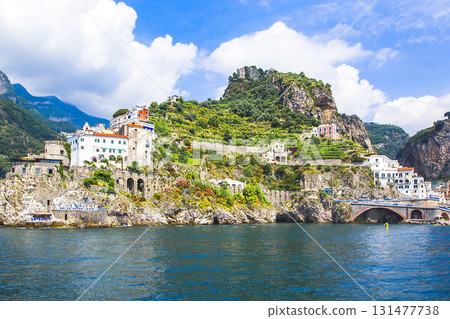 Panoramic view, aerial skyline of small haven of Amalfi village with tiny beach and colorful houses located on rock. Tops of mountains on Amalfi coast, Salerno, Campania, Italy. Panoramic view, aerial skyline of small haven of Amalfi village with tiny beach and colorful houses located on rock. Tops of mountains on Amalfi coast, Salerno, Campania, Italy. 131477738
