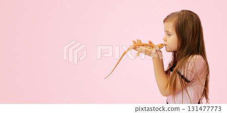 Portrait of pretty girl with Red bearded Agama iguana on pink background. Little child playing with reptile. Selective focus. Banner, copy space. High quality photo Portrait of pretty girl with Red bearded Agama iguana on pink background. Little child playing with reptile. Selective focus. Banner, copy space. High quality photo 131477773