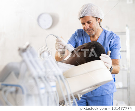 African man client undergoes facial skin care procedure using nozzle cold hammer whitening African man client undergoes facial skin care procedure using nozzle cold hammer whitening 131477774