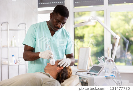 Man client undergoes facial skin care procedure using nozzle cold hammer whitening 131477780