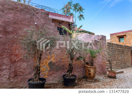 Street view of old town of Rhodes, Greece. Pots with flowers standing on paved pavement along stone wall. High quality photo 131477820