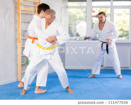Aged man working on jiu-jitsu techniques in training fight with young rival Aged man working on jiu-jitsu techniques in training fight with young rival 131477836