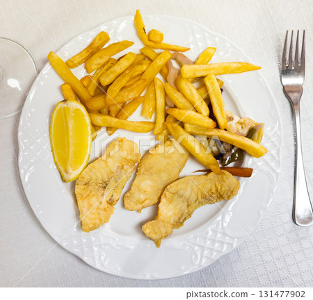 Battered fish with lemon and potatoes Battered fish with lemon and potatoes 131477902