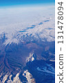View from window of plane to blue sky and snowy mountain peaks in white clouds. High quality photo 131478094