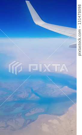 View from the window of plane on blue sky and earth with landscape of desert, sea and canals in Emirates. High quality photo 131478098