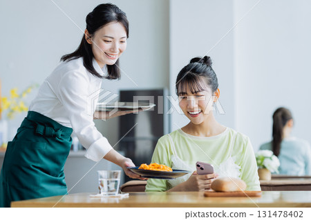 一個年輕的女人在咖啡館吃飯 一個年輕的女人在咖啡館吃飯 131478402