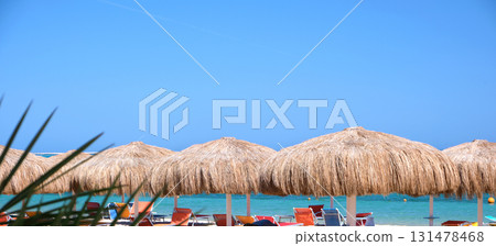 Straw shade umbrella in sea tropical region against blue vibrant sky in summer Straw shade umbrella in sea tropical region against blue vibrant sky in summer 131478468