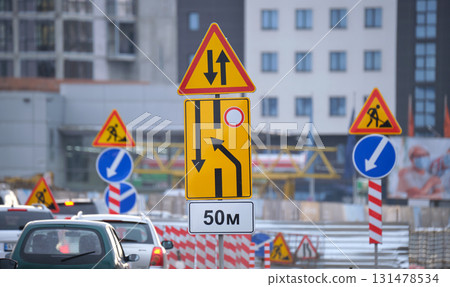 Roadworks warning traffic signs of construction work on city street and slowly moving cars 131478534