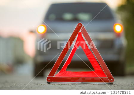 Red emergency triangle stop sign and broken car on a city street. Red emergency triangle stop sign and broken car on a city street. 131478551