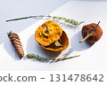Dried pumpkin - container with a lid and a dried mandarin with a leaf, horsetail, and a spruce cone on a white background. Still life. 131478642