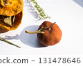 Dried pumpkin - container with a lid and a dried mandarin with a leaf, horsetail, and a spruce cone on a white background. Still life. 131478646