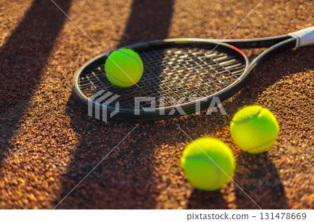 Tennis ball with rocket near grid at outdoor summer sunny court closeup Tennis ball with rocket near grid at outdoor summer sunny court closeup 131478669
