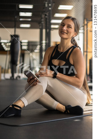 Fitness woman relaxing on mat use smartphone chatting at gym enjoy break 131478695