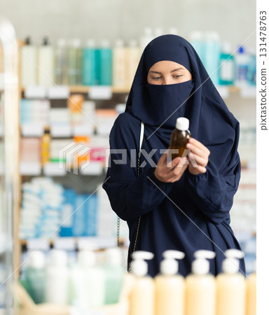 Young Muslim woman choosing cough syrup at pharmacy Young Muslim woman choosing cough syrup at pharmacy 131478763