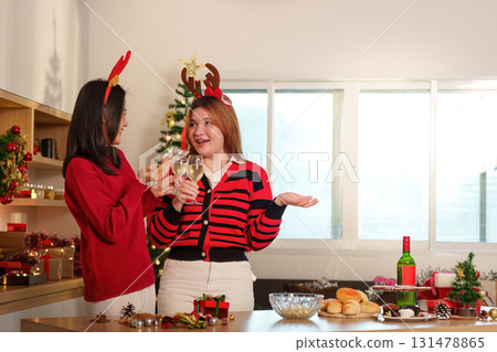 Festive Gathering. Friends toasting with drinks in a beautifully decorated kitchen. 131478865