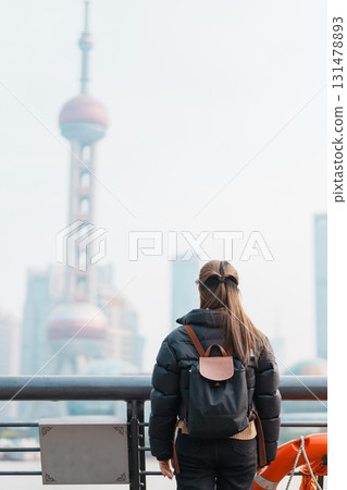 woman traveler visiting in Shanghai, China. Female Tourist with backpack sightseeing Shanghai view of Lujiazui in The Bund of Shanghai. landmark and popular for tourism attractions. Vacation concept 131478893
