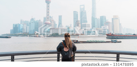 woman traveler visiting in Shanghai, China. Female Tourist with backpack sightseeing Shanghai view of Lujiazui in The Bund of Shanghai. landmark and popular for tourism attractions. Vacation concept 131478895