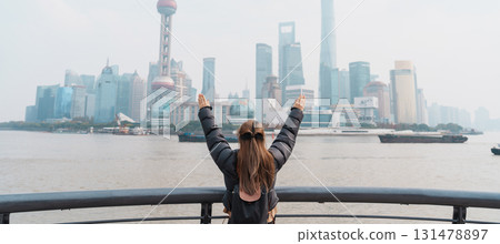 woman traveler visiting in Shanghai, China. Female Tourist with backpack sightseeing Shanghai view of Lujiazui in The Bund of Shanghai. landmark and popular for tourism attractions. Vacation concept 131478897