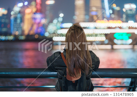 woman traveler visiting in Shanghai, China. Female Tourist with backpack sightseeing Shanghai view of Lujiazui in The Bund of Shanghai at night. landmark and popular for tourism attractions 131478905