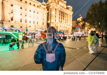 woman traveler visiting in Shanghai, China. Happy Female Tourist sightseeing Shanghai view in The Bund of Shanghai at night. landmark and popular for tourism attractions. Travel and Vacation concept 131478909