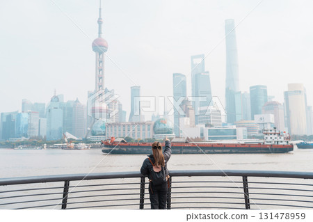woman traveler visiting in Shanghai, China. Female Tourist with backpack sightseeing Shanghai view of Lujiazui in The Bund of Shanghai. landmark and popular for tourism attractions. Vacation concept woman traveler visiting in Shanghai, China. Female Tourist with backpack sightseeing Shanghai view of Lujiazui in The Bund of Shanghai. landmark and popular for tourism attractions. Vacation concept 131478959