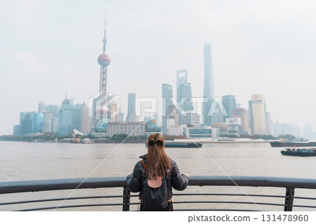 woman traveler visiting in Shanghai, China. Female Tourist with backpack sightseeing Shanghai view of Lujiazui in The Bund of Shanghai. landmark and popular for tourism attractions. Vacation concept 131478960