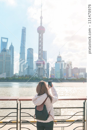 woman traveler visiting in Shanghai, China. Female Tourist with backpack sightseeing Shanghai view of Lujiazui in The north Bund of Shanghai. landmark and popular for tourism attractions 131478976