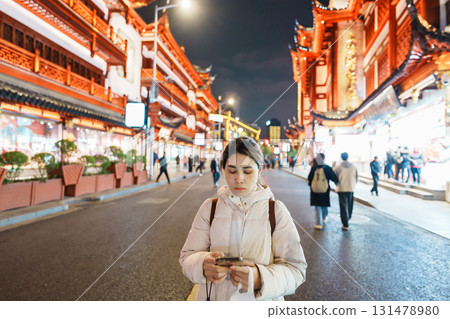 woman traveler visiting in Shanghai, China. Happy Female Tourist sightseeing and shopping in Yuyuan Old Street market at night. landmark and popular for tourism attractions. Travel and Vacation 131478980