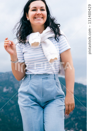Smiling Woman in Striped Shirt and Light Blue Pants Enjoying Outdoor Walk on a Cloudy Day Smiling Woman in Striped Shirt and Light Blue Pants Enjoying Outdoor Walk on a Cloudy Day 131480429