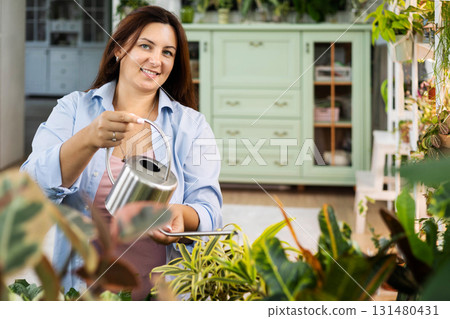 Unrecognizable woman gardener florist growing care use watering can at home indoor garden closeup 131480431