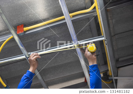 Worker is installing metal profiles for gypsum board ceiling in renovate house. Worker is installing metal profiles for gypsum board ceiling in renovate house. 131481182
