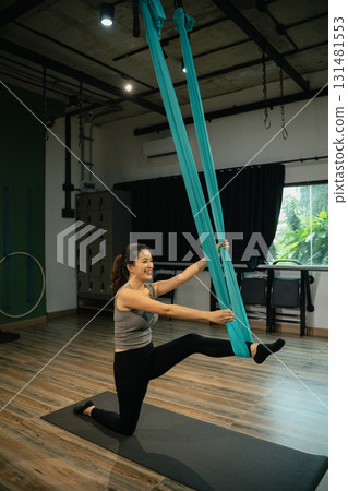 Young woman practicing aerial yoga using hammock in studio. Concept of wellness and mindfulness 131481553