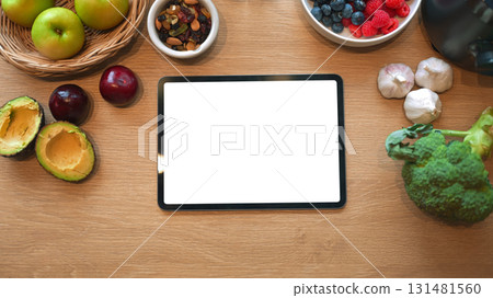 Digital tablet with blank screen surrounded by organic food ingredients, for diet planning or nutrition app display Digital tablet with blank screen surrounded by organic food ingredients, for diet planning or nutrition app display 131481560