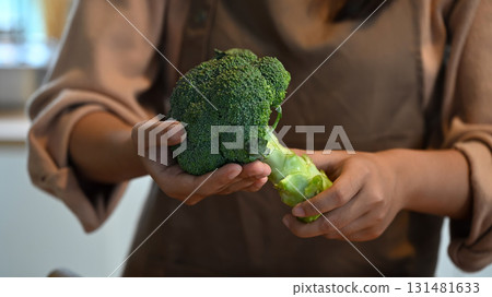Close up of woman holding fresh broccoli, healthy organic vegetable for cooking and clean eating 131481633