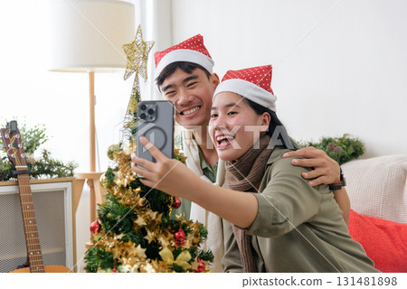 Christmas holiday brings happy young couple joy, sharing love, enjoying winter fun, taking selfie at home, celebrating with decorated Christmas tree. Christmas holiday brings happy young couple joy, sharing love, enjoying winter fun, taking selfie at home, celebrating with decorated Christmas tree. 131481898