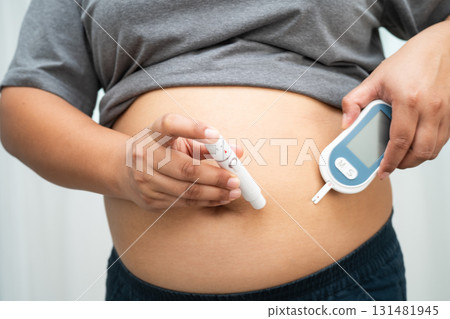 Asian woman injecting herself diabetes injecting insulin in stomach at home. 131481945