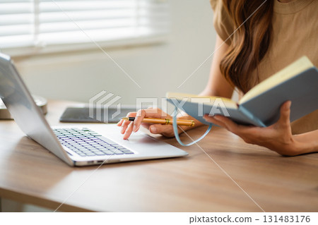 Female businessman working with holding a pen and using a calculator to calculate the numbers of static at home office. Female businessman working with holding a pen and using a calculator to calculate the numbers of static at home office. 131483176