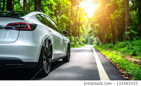 Electric car driving along a serene road surrounded by lush nature on a sunny day Electric car driving along a serene road surrounded by lush nature on a sunny day 131483335