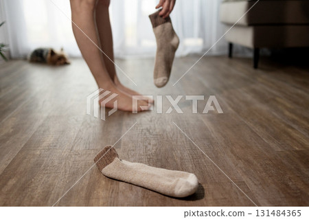 Woman Putting on Socks at Home With Underfloor Heating in Living Room Woman Putting on Socks at Home With Underfloor Heating in Living Room 131484365