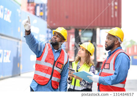 Group of men and women of professional container operators standing in shipping container yard look at the camera and show thumbs up. Logistic staff work at container cargo sites and checking 131484657