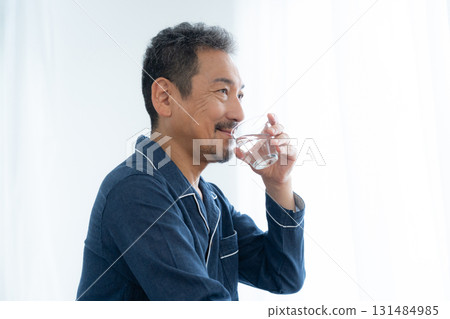 Middle-aged man drinking water in his bedroom Middle-aged man drinking water in his bedroom 131484985