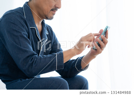 Middle-aged man looking at smartphone in bedroom 131484988
