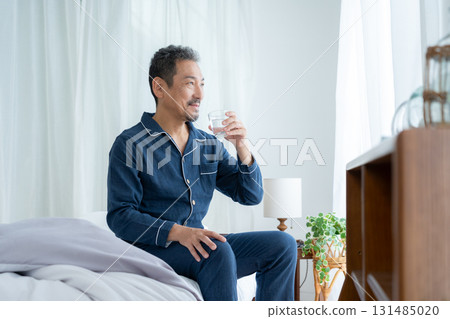 Middle-aged man drinking water in his bedroom 131485020