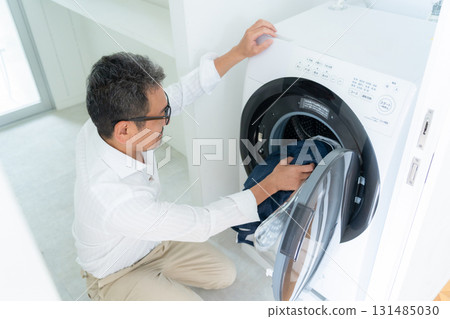 Middle-aged man doing laundry Middle-aged man doing laundry 131485030