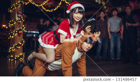 A woman dressed as Santa Claus and a man dressed as a reindeer 131486457