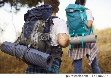 Close view of couple hikers with backpacks and mats trekking a dry forest trail 131486683