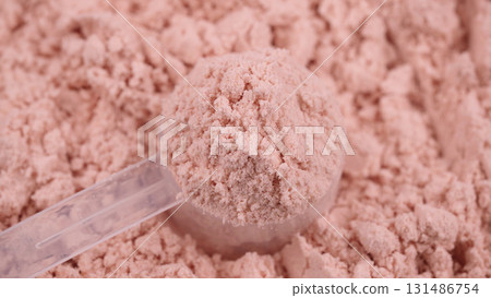 Close-up of a plastic scoop filled with whey pink protein powder on a textured background. Strawberry flavored sports supplement, fitness nutrition, healthy diet concept. Bodybuilding gym lifestyle Close-up of a plastic scoop filled with whey pink protein powder on a textured background. Strawberry flavored sports supplement, fitness nutrition, healthy diet concept. Bodybuilding gym lifestyle 131486754