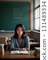 An Asian woman is seated alone at a table in the room, engaged in reading a book 131489334