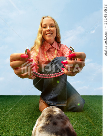 Smiling woman showing pink dog collar from animal playful ground-level view 131489618